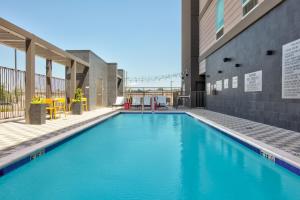 亨茨维尔Home2 Suites By Hilton Huntsville, Tx的一座大型蓝色游泳池,位于大楼旁边