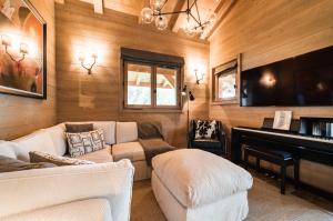 梅杰夫Luxury Megève Chalet, sleeps 8 with Mountain Views and Jacuzzi的带沙发和钢琴的客厅