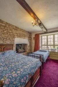 卡尔迪科特Medieval Manor的一间卧室设有两张床和石墙