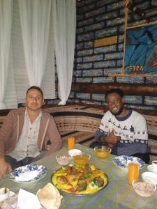 瓦迪穆萨Petra Anas House的两个人坐在桌子上,拿着一盘食物