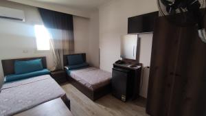 艾斯尤特فندق أجياد Agyad Hotel的一间小房间,配有两张床和一台小冰箱