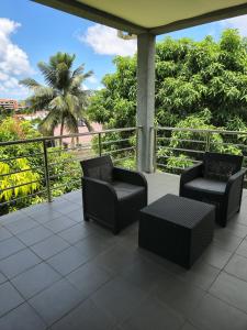 格罗斯岛Belle Luxury Apartments的棕榈树阳台的两把椅子和一张桌子