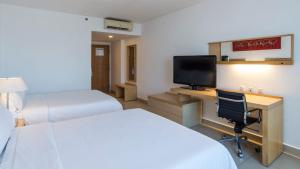曼萨尼约曼萨尼约智选假日酒店的酒店客房设有两张床和一张书桌及电视