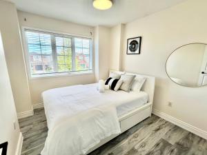 多伦多Cozy house near 401 & Go station的白色卧室配有一张带镜子的大床