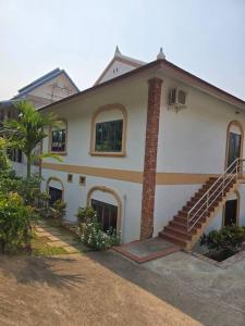琅勃拉邦#5 Appartement meublé + piscine.的白色的房子,前面有楼梯