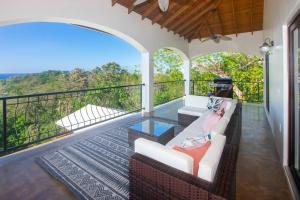 罗阿坦Apricari Villa / Luxury Views / 5 BDRM / Pool的客房设有一个带沙发和桌子的阳台。