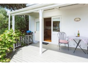 欧尼罗亚Romantic Cottage Recommended by NZ Herald的白色门廊,配有桌子和椅子