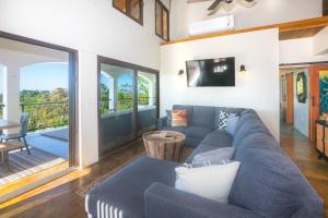 罗阿坦Apricari House Stunning Views 3 BDRM and Pool的客厅配有蓝色的沙发和电视