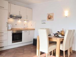 诺德代希Windrose Comfortable holiday residence的厨房配有木桌和白色橱柜。