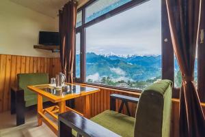 MunsyariGoroomgo Bala Paradise Munsyari - Himalayan View Room的客房设有桌椅和大窗户。