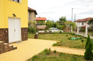 贝尔科维察Guest House Nocturno的后院设有黄色的房子和花园
