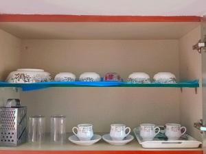 迈索尔Kailash Guest Home的上面有杯子和碟子的架子
