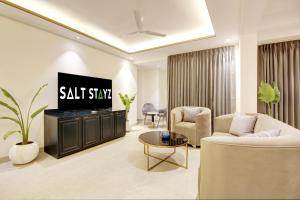 古尔冈Saltstayz Amara - Near MG Road and Sector 29的客厅配有电视、沙发和桌子