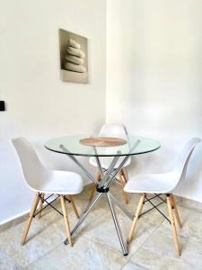 科莫蒂尼Crystal Clear - 2 separate bedrooms and PARKING的玻璃桌和两张白色椅子