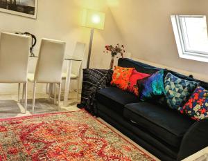 AddingtonPrivate apartment in a big bungalow in Selsdon!的客厅里一张带色彩缤纷枕头的黑色沙发