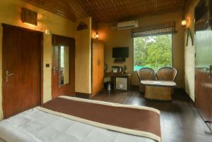 MarchulaTashree Kabeela Riverside Resort的一间卧室配有一张床、两把椅子和一个窗户