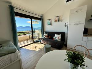 波尔蒂乔Studio Vue Mer - Piscine - Porticcio的客厅配有沙发和美景窗户。