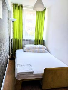 华沙Ursus Rooms-Self Check-in的绿窗帘和窗户的客房内的一张床位