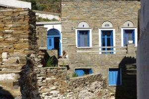 ÓrmosAndros Stone Cottage, garden and sea view的坐在石头建筑的顶端的女人