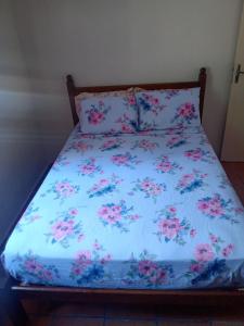 塞拉内格拉Campo dos Sonhos的一张带粉红色花卉的蓝色棉被的床