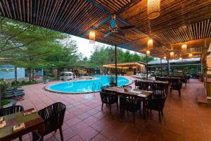 Ðá LònChay Lap Farmstay Phong Nha的一个带桌子的室外餐厅和一个游泳池