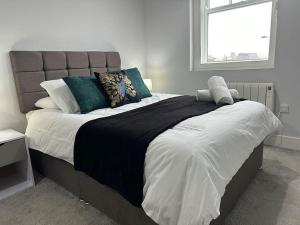 布伦特伍德Spacious, bright, modern flat的卧室配有带枕头的大床和窗户。