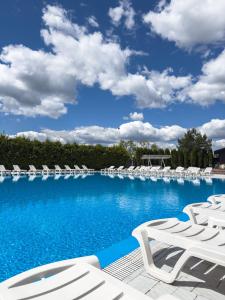 YelikhovichiAvalon Hotel&Pool的一个带白色椅子和蓝色天空的大型游泳池