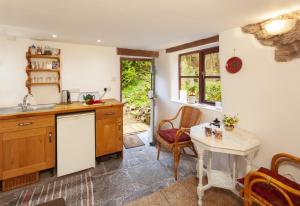 威弗利斯科姆Garden Cottage, Wiveliscombe的厨房配有水槽和桌椅