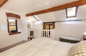 威弗利斯科姆Garden Cottage, Wiveliscombe的一间卧室设有一张床和两个窗户。