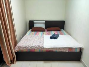 Thung Si Kanป็อปปูล่าคอนโด เมืองทองธานี ใกล้ Impact 酒店 公寓的一张带黑色床头板和一双鞋的床