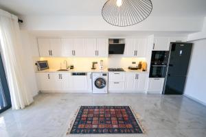 费特希耶Oasis Family-Friendly Luxury Villa Fethiye Oludeniz by Sunworld Villas的厨房配有白色橱柜和黑色冰箱。