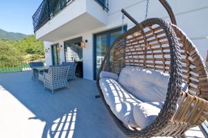 费特希耶Oasis Family-Friendly Luxury Villa Fethiye Oludeniz by Sunworld Villas的门廊上的柳条秋千椅和桌子
