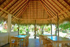 内布拉拉Mulia Bungalows的一间设有桌子和椅子的稻草屋顶餐厅