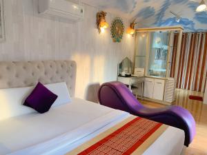 永隆NGỌC HƯNG HOTEL的一间卧室配有一张带紫色椅子的床