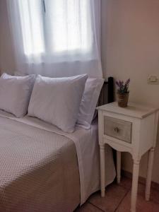尼基亚娜Evi's house的一张带白色枕头的床和一个窗边的床头柜