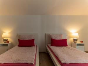 泰特南Ferienwohnung Elena的宿舍间内的两张床,配有红色枕头和灯具