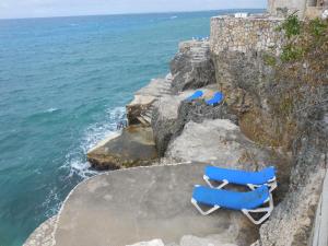 尼格瑞尔home sweet home resort的三个蓝色躺椅坐在靠近海洋的悬崖上