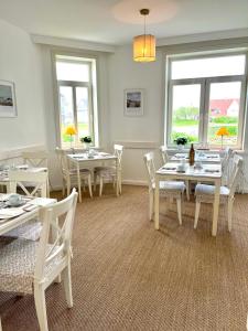 文尼斯塔特Hotel Villa Klasen的一间设有白色桌椅和窗户的用餐室