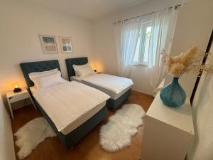 马卡尔斯卡Luxury apartments Nikolina Sea&City view的卧室配有两张床,地板上设有一个花瓶。