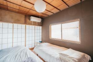 松本松本市の一棟貸し切りできる古民家的一间卧室设有两张床和窗户。