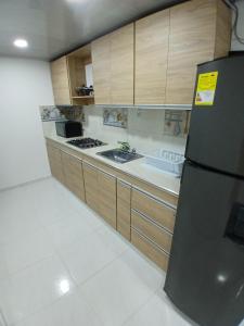Buenavistaposada kyca cerca ala playa的厨房配有黑色冰箱和木制橱柜。