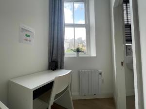 科克Cork city En-suite Single room的白色的客房设有窗户,配有一张白色的书桌。