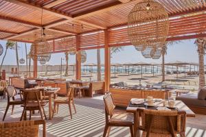 塞拉莱The Club by Fanar的一间带桌椅的餐厅,享有海滩美景