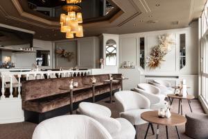 布兰肯贝赫海滩宫廷酒店的一间设有白色桌椅的餐厅和一间酒吧