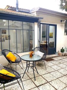 巴黎Artist's Home - Villa & Private Courtyard - 200m2的庭院配有三把椅子和一张带黄色枕头的桌子。