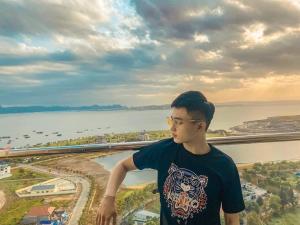 下龙湾Homestay Ha Long Luxury Apartment ( Ocean View)的站在一个水景阳台上的年轻人