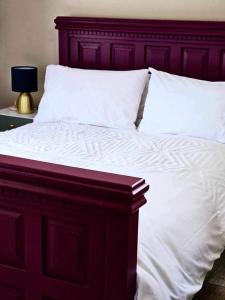 邓多克Croí Beag Luxury Studio的一张配有白色床单和木制床头板的大床