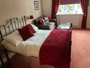 彻奇斯特雷顿Birchwood House的一间卧室配有一张带红色枕头的床和一张沙发