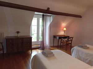 Le Grand VireyLe Nid des Tourterelles的一间卧室设有两张床、一张桌子和一个窗口。