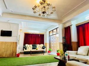 西姆拉Hotel Tara Regency - A family Hotel的客厅配有吊灯和红色窗帘